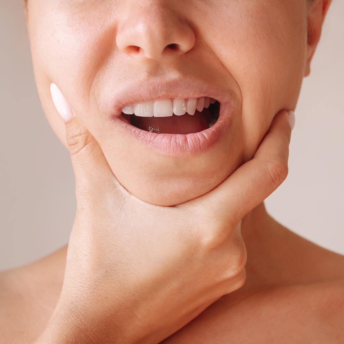 Cropped shot of a young woman suffering from jaw pain holding he Cropped shot of a young woman suffering from jaw pain holding he